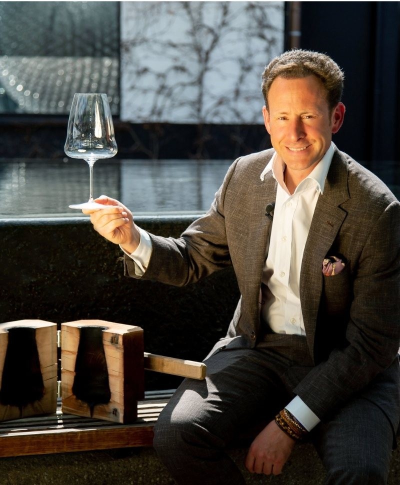 Foto von Maximilian j. Riedel, der ein Weinglas in der Hand hält