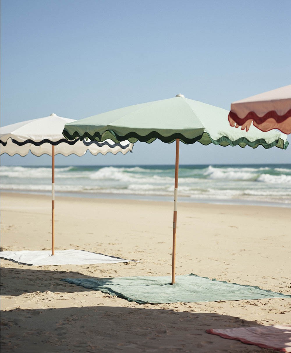 Moodbild des Sonnenschirms Amalfi Beach Umbrella  im Rivie Green Design aus der 2024 Sommer Kollektion von Business & Pleasure im RAUM concept store.
