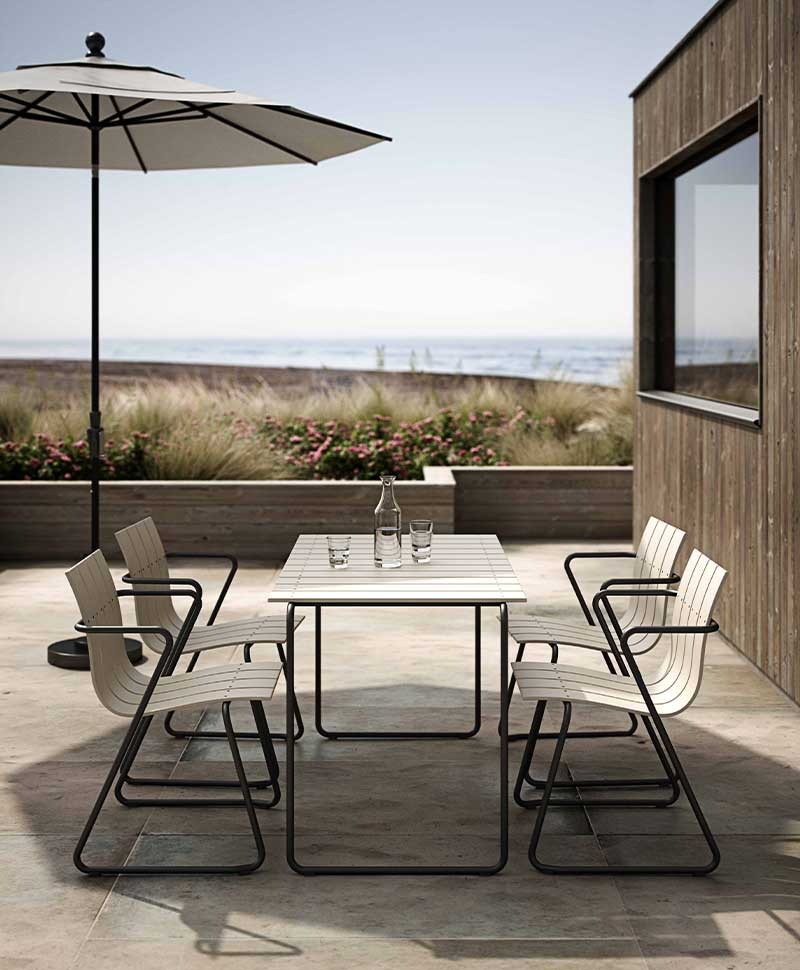 Weiße Ocean Chairs von Mater stehen zusammen mit dem passenden Tisch auf der Veranda eines kleinen Strandhauses 