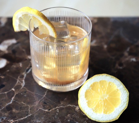 Ein Whiskey Spur wurde in einem Tumbler Glas von knIndustrie hergerichtet zusammen mit Zitronenscheiben auf eine schwarze Marmorunterlage gestellt