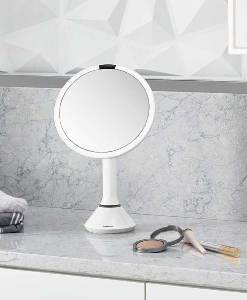 Moodbild des Badspiegels Sensor von Simplehuman, der auf einer Kommode steht und von Kosmetikartikeln umringt ist