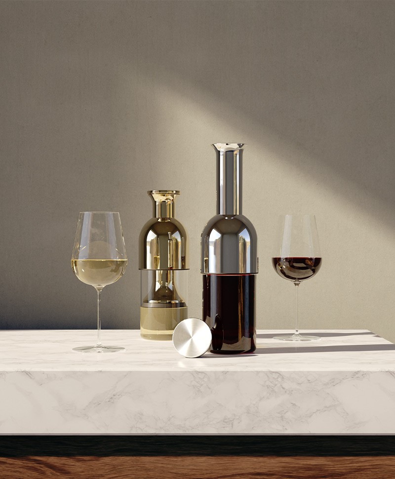 Ein Rotweindekanter und ein Gefäß mit Weißwein neben einem Glas Weißwein und einem Glas Rotwein