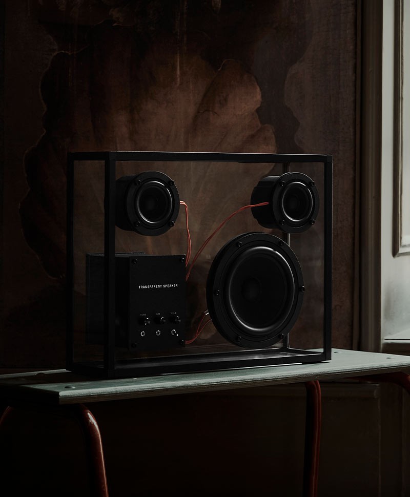 schwarzer Transparent Loudspeaker auf einem schwarzen Beistelltisch vor einer dunklen Wand