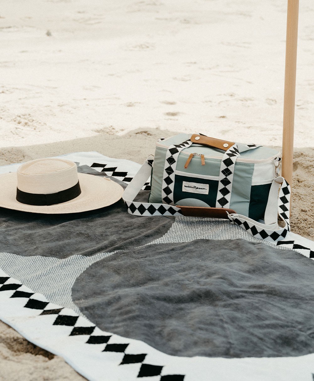 Moodbild des Strandtuchs „Beach Towel“ und der Kühltasche „Premium Cooler“ im grünen Diamond Design aus der 2023 Sommer Kollektion von Business&Pleasure im RAUM concept store.