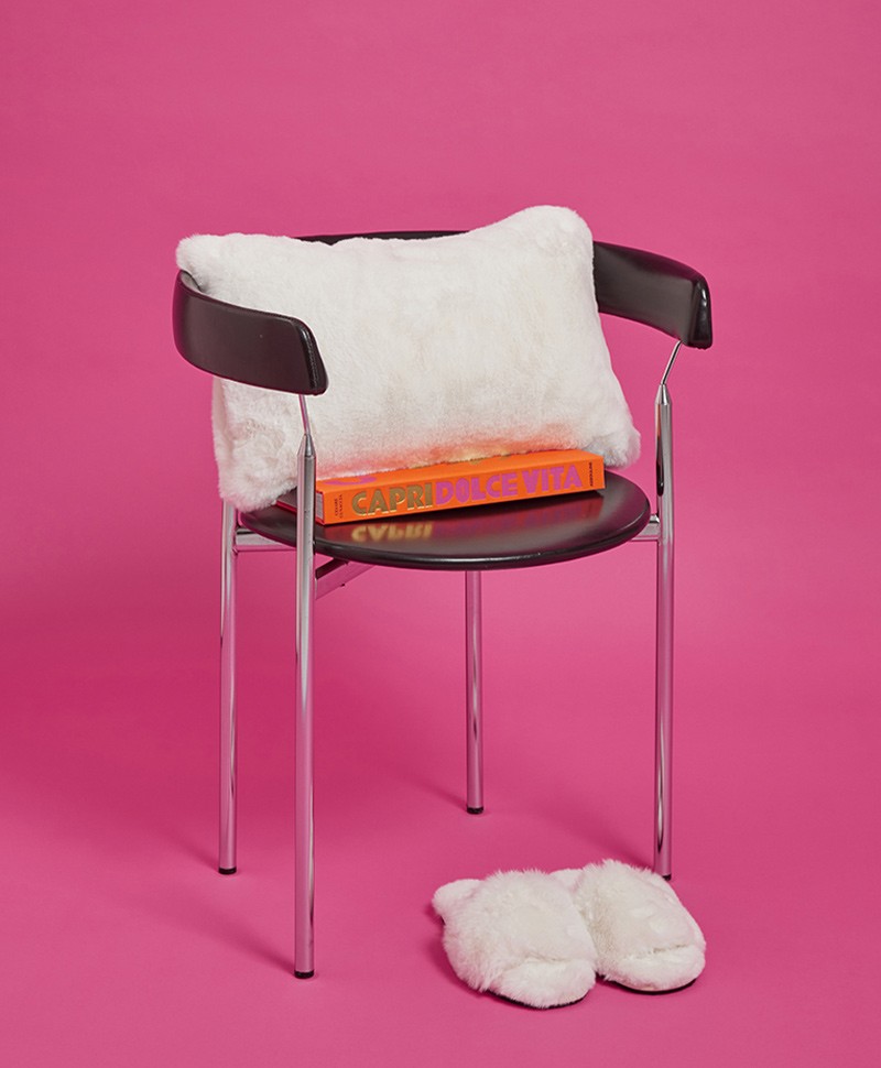 Das Moodbild zeigt das Kissen Cicly aus Kunstfell von der Marke Apparis in der Farbe ivory auf einem Stuhl – im Onlineshop RAUM concept store