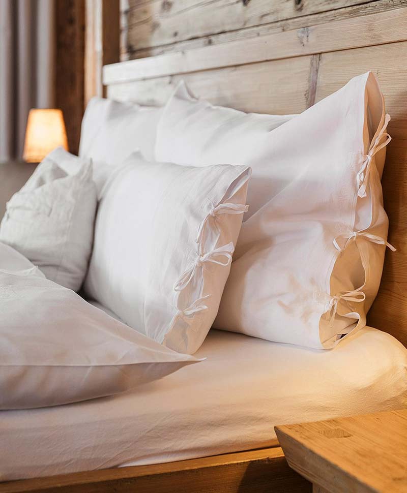 Bett in einem rustikalen Hotelzimmer mit Holzvertäfelung und Leinenbettwäsche von Indradanush