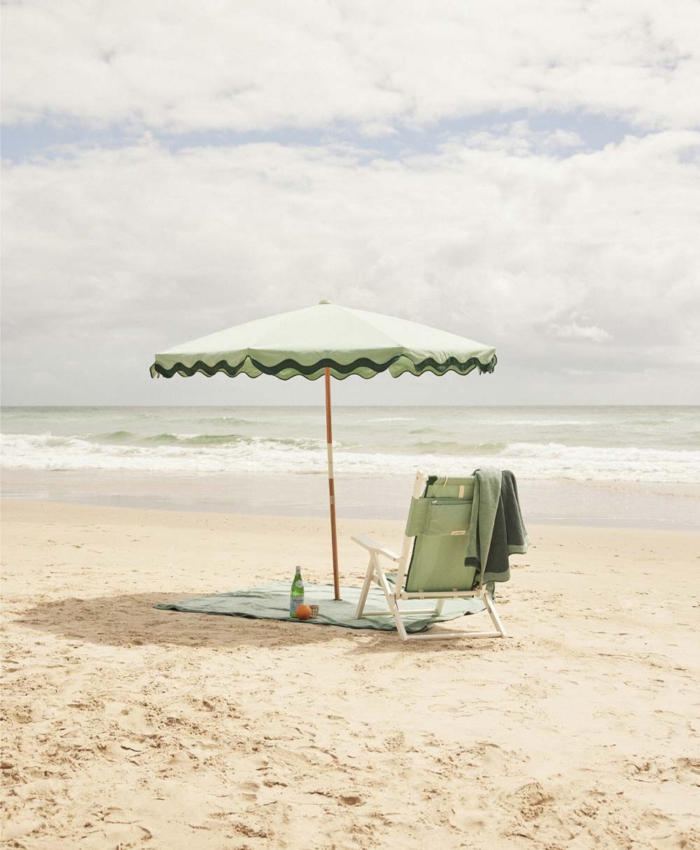 Moodbild des Sonnenschirms Amalfi Beach Umbrella  im Rivie Green Design aus der 2024 Sommer Kollektion von Business & Pleasure im RAUM concept store.