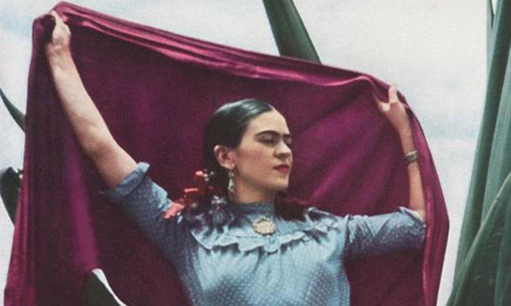 Bannerbild, das Frida Kahlo zeigt, die mit ausgebreiteten Armen ein rotes Tuch hochhält
