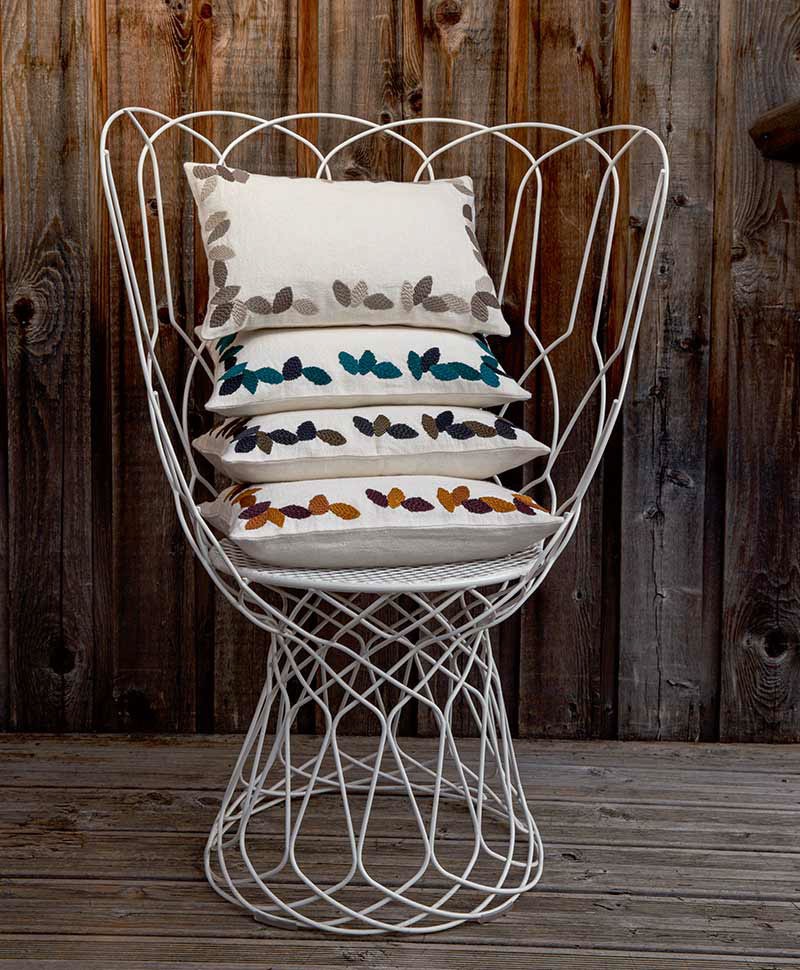 Das Moodbild zeigt die Kissen Sherwood auf einem Sessel  in den verschiedenen Farbvarianten von Élitis – im Onlineshop RAUM concept store