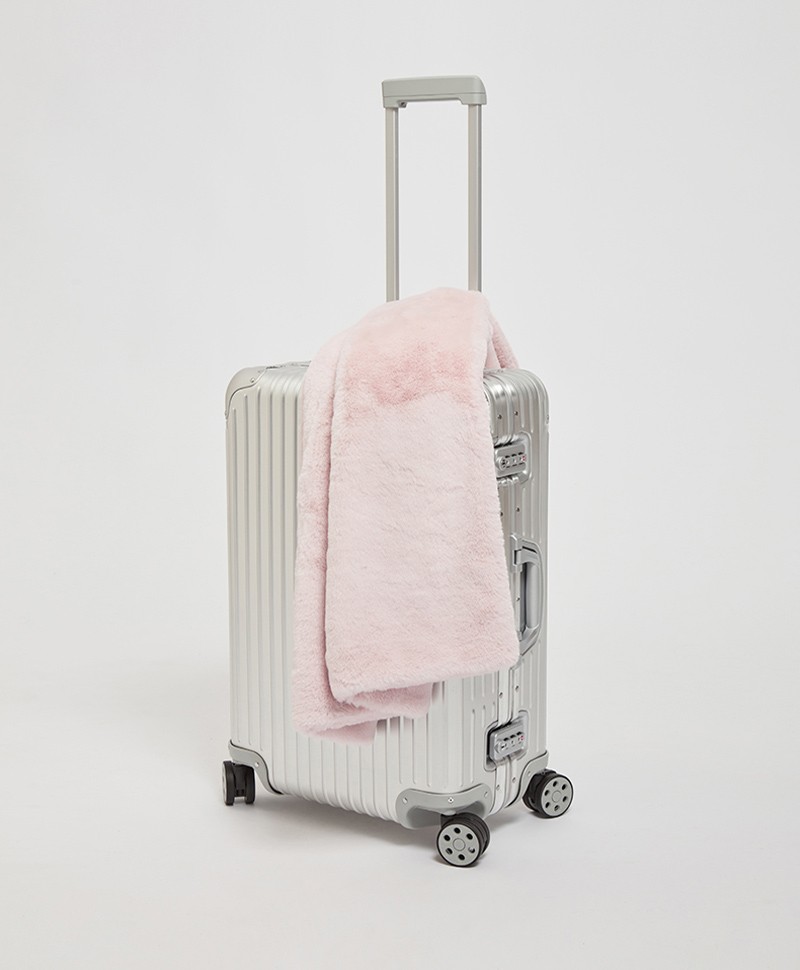 Das Moodbild zeigt die Decke Brady aus Kunstfell von der Marke Apparis in der Farbe blush auf einem Koffer – im Onlineshop RAUM concept store