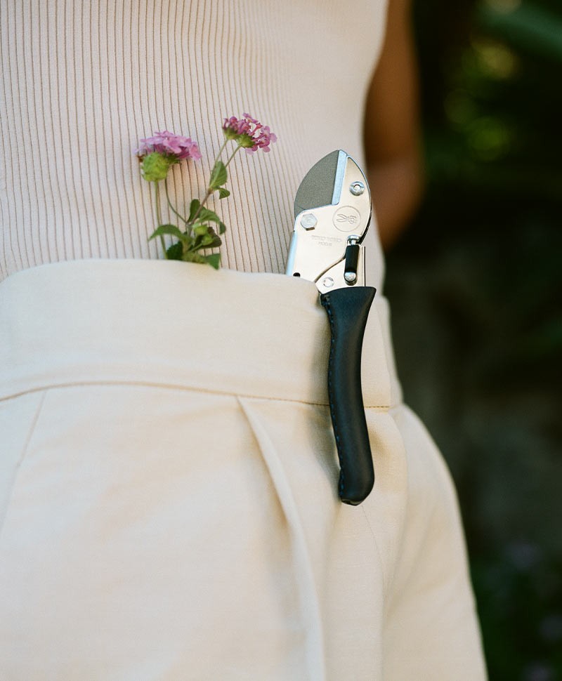 Eine Gartenschere von Chop Chop Bloom steckt neben einer Blume in einer Hose