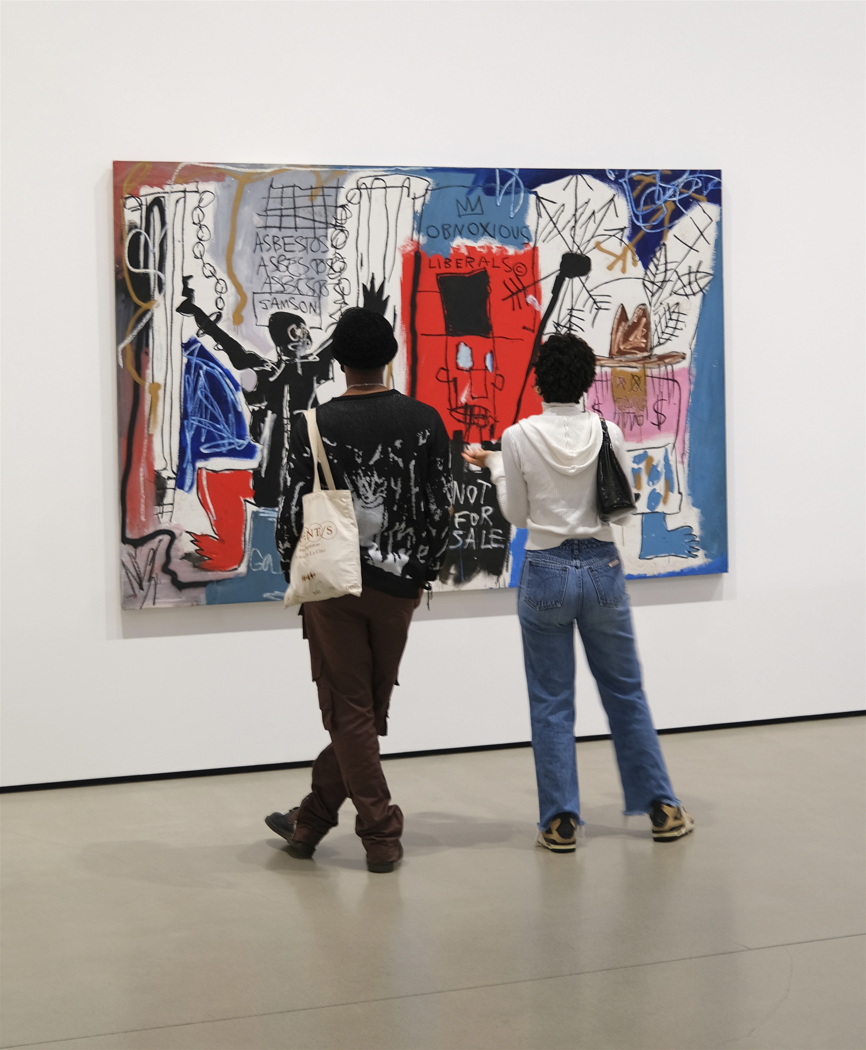Zwei Personen bewundern ein Bild von Jean Michel Basquiat in einer Galerie