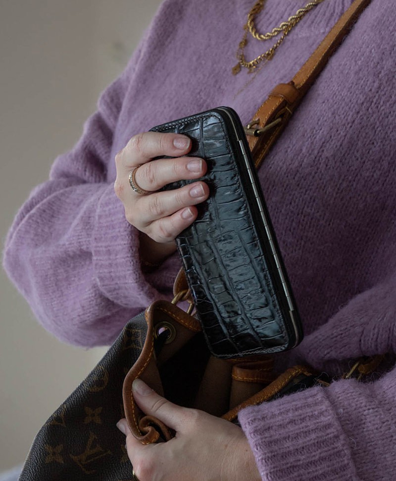 Das Moodlbild zeigt eine Frau, die das schwarze  Croc Cowhide Manicure Frame L – Maniküre-Etui Kroko Kalbleder von F.Hammann in ihre Tasche steckt – im Onlineshop RAUM concept store