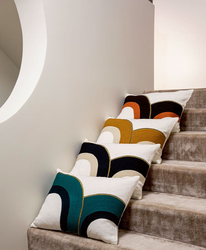Das Moodbild zeigt die Kissen Bridge in in den verschiedenen Farbvarianten von Élitis auf einer Treppe – im Onlineshop RAUM concept store