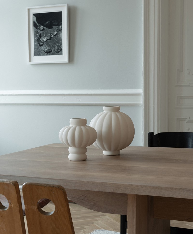 Moodbild, das zwei Balloon Vasen in verschiedenen Größen in der Farbe sanded grey zeigt, die dekorativ auf einem Holztisch stehen
