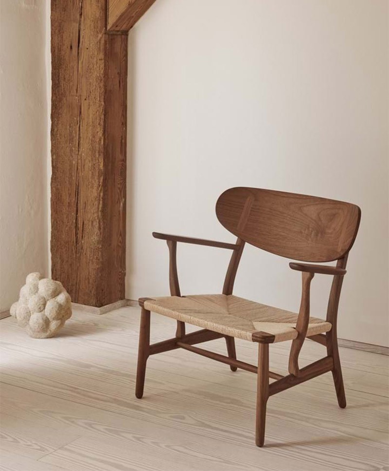 Ein Wishbone Chair von Carl Hansen and Son vor einer weißen Wand auf einem Holzboden