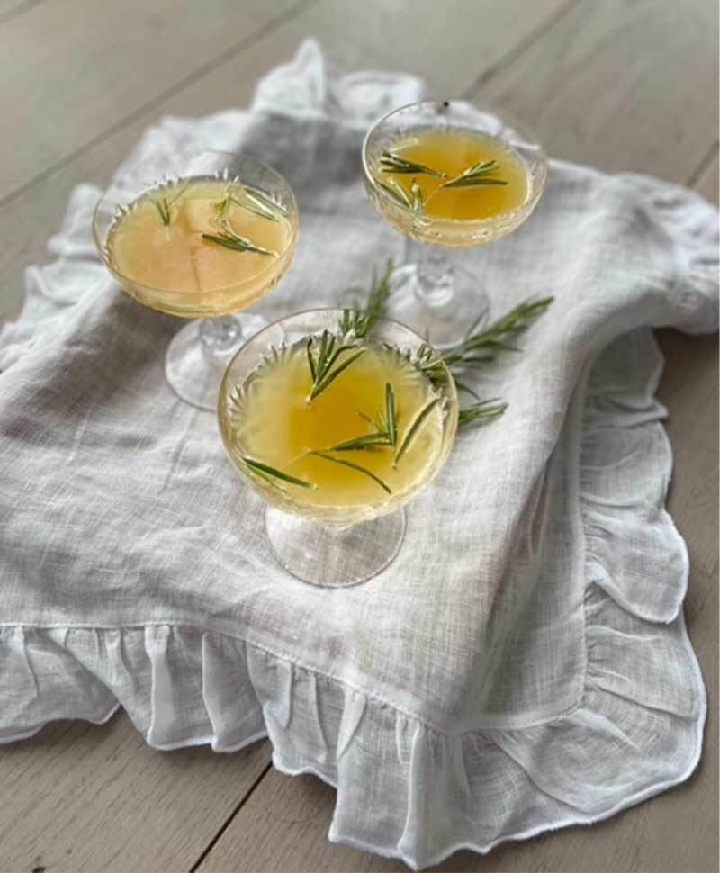 Drei Gläser des Ayurveda Sommer Spritz nach dem Rezept von Ulrike Dreier stehen auf einem kleinen Tablett mit Leinentuch