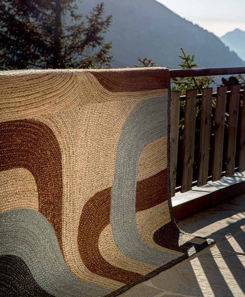 Das Moodbild zeigt den Teppich Penny Lane in der Farbe Nuage über einem Geländer von Élitis im RAUM concept store