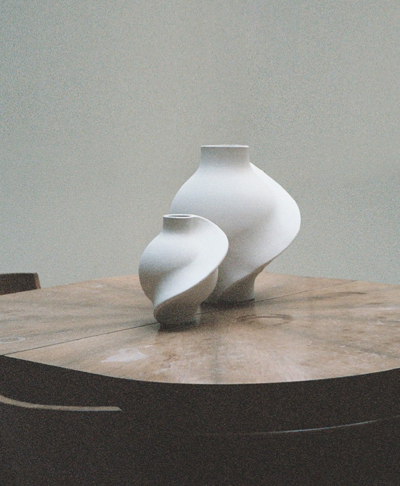 Moodbild, das zwei Pirout Vasen von Louise Roe in der Farbe white  zeigt, die auf einem runden Holztisch stehen