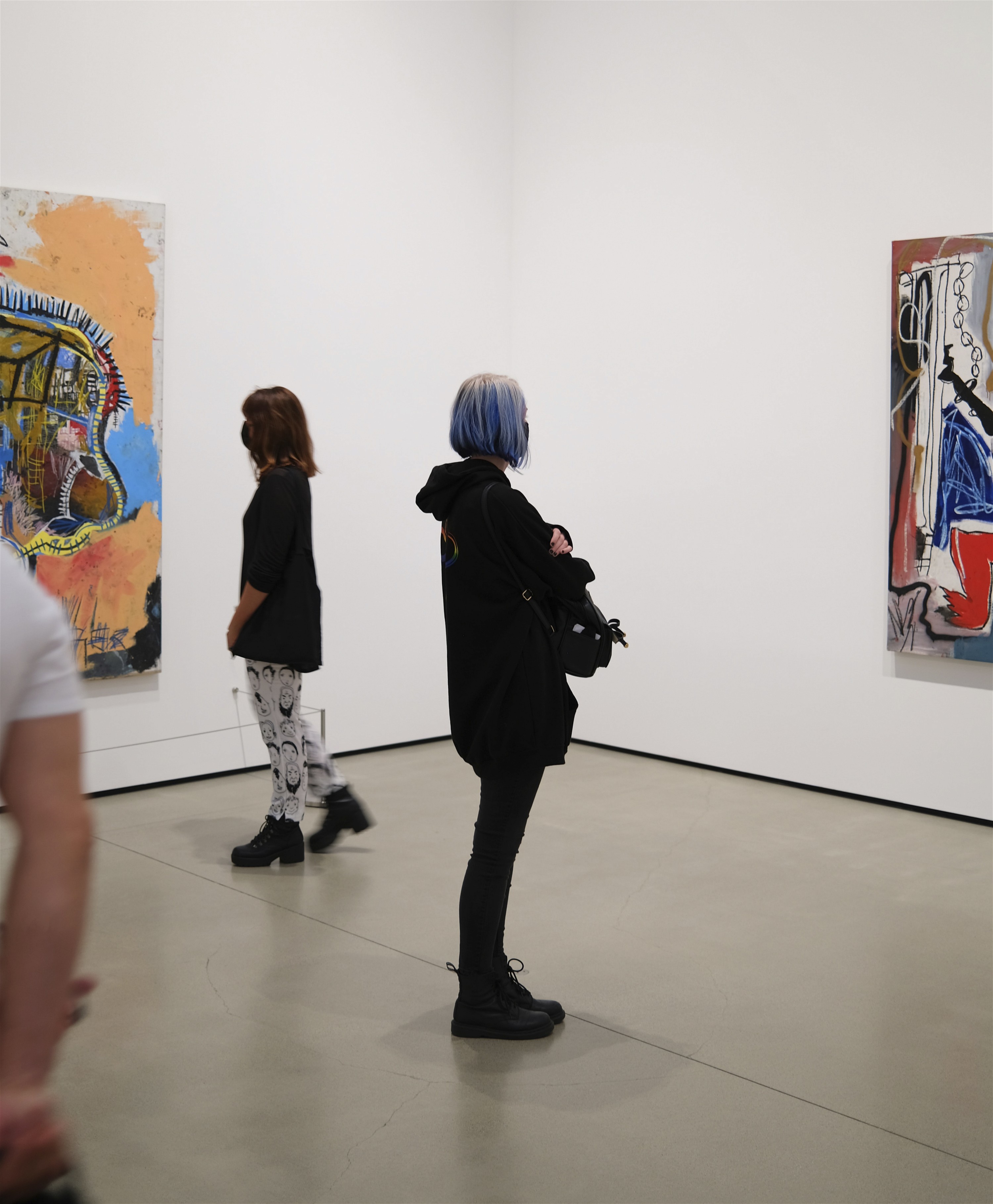 Personen betrachten Bilder von Jean Michel Basquiat bei einer Ausstellung