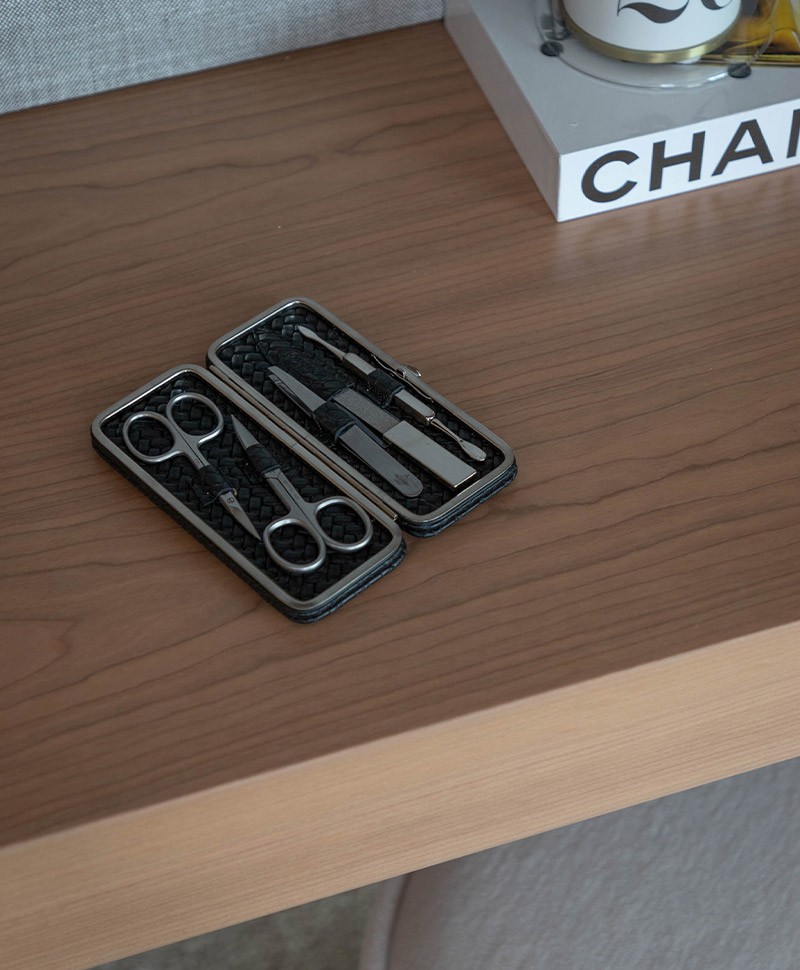 Das Moodfoto zeigt das Woven Manicure Frame M – Maniküre-Etui Flechtleder von F.Hammann in der Farbe black auf einer Ablage aus Holz – im Onlineshop RAUM concept store